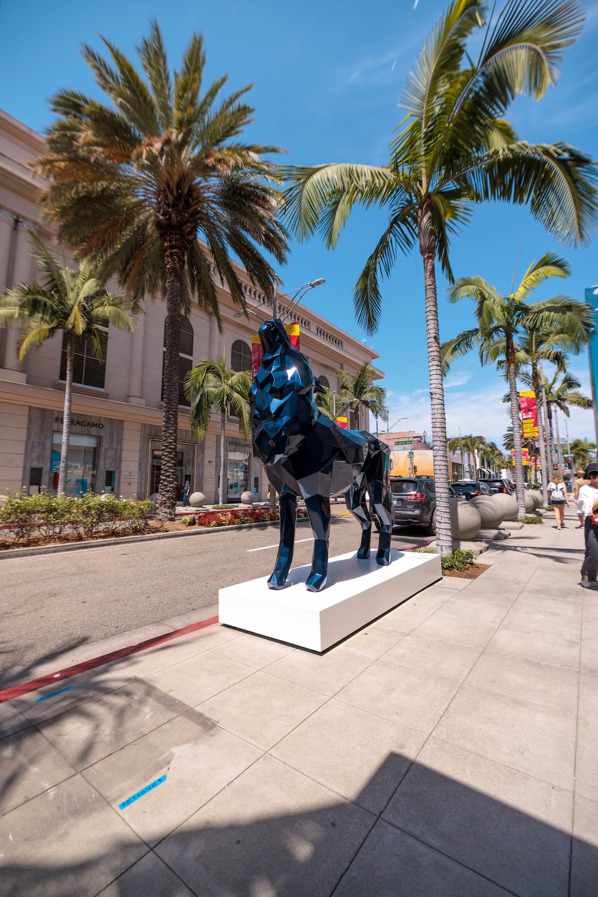 Richard Orlinski's blue Howling Wolf sculpture framed by palm trees